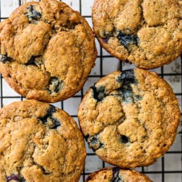 Four banana blueberry muffins on a wire rack.
