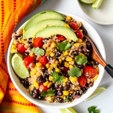 Quinoa Salad in a white bowl topped with avocado slices.