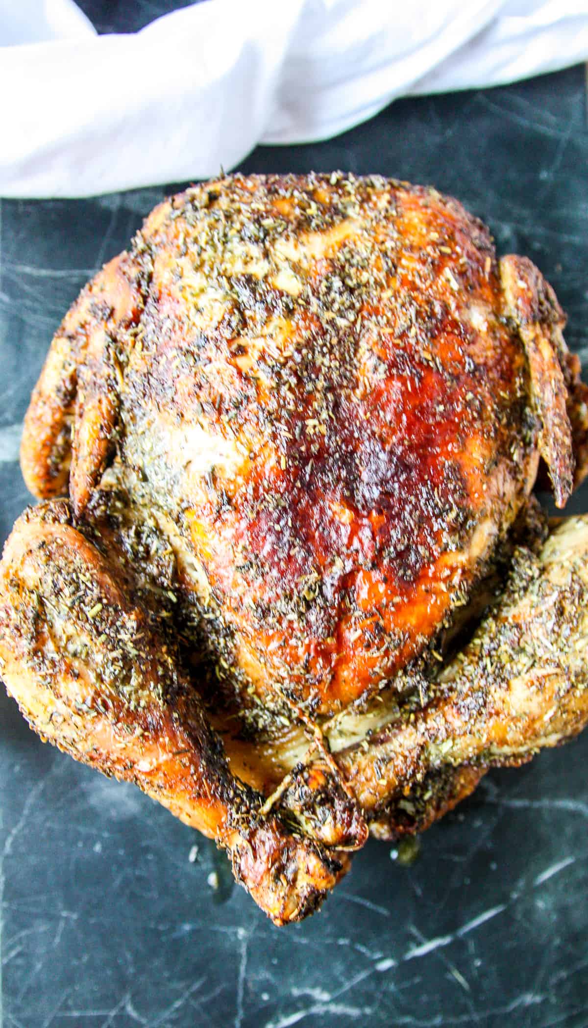 A fully cooked air fryer whole chicken on a marble board.