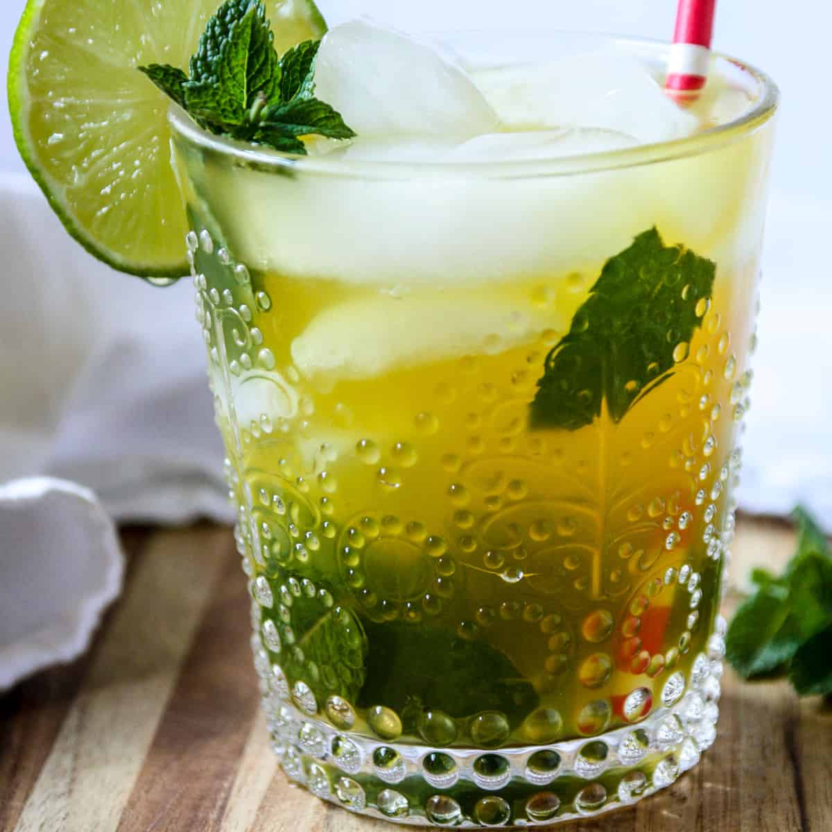 A mango mojito in a clear glass with a red straw.
